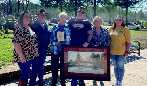 Merle Cox, Jr.'s family hold his dedication plaque and portrait during the dedication ceremony. Courtesy photo