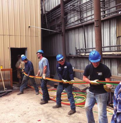 Crew members work hard to reroute wiring to the machines to get them fully operational after the April 22 tornado damaged the business. Courtesy Photo