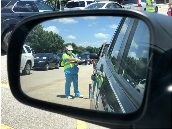 Workers at a mobile COVID-19 test site in Norman placed patient paperwork on windshields until cars reached the front of the line. The information is then retrieved and matched up with a number on a test tube that will hold the sample taken through a nasal swab. (Whitney Bryen/Oklahoma Watch)