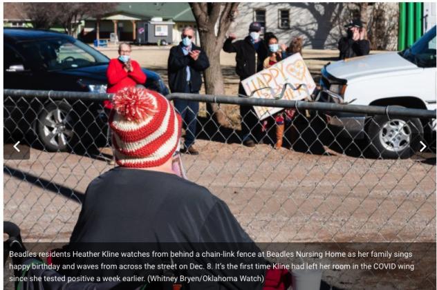 Beadles residents Heather Kline watches from behind a chain-link fence at Beadles Nursing Home as her family sings happy birthday and waves from across the street on Dec. 8. It’s the first time Kline had left her room in the COVID wing since she tested positive a week earlier. (Whitney Bryen/Oklahoma Watch)