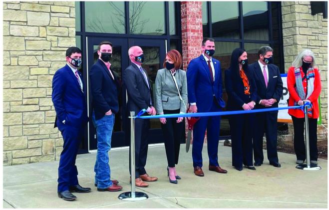 Oklahoma Gov. Kevin Stitt, center holding scissors, and state cabinet secretaries pose during a Jan. 21 ribbon-cutting ceremony at the newly relocated state Public Health Lab in Stillwater. (Oklahoma State Department of Health)