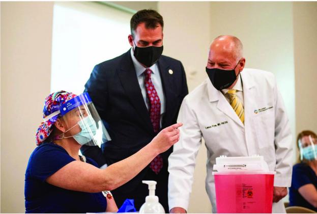 ICU nurse Erica Arrocha shows Gov. Kevin Stitt and Oklahoma State Commissioner of Health Dr. Lance Frye before administering the state's first COVID-19 vaccine at Integris Baptist Medical Center in Oklahoma City on Dec. 14, 2020. (Whitney Bryen/Oklahoma Watch)