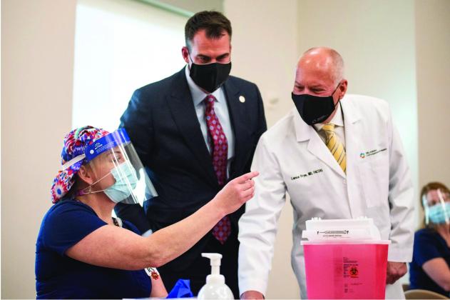 In this file photo, Oklahoma State Commissioner of Health Dr. Lance Frye, right, is shown with Gov. Kevin Stitt, middle and ICU nurse Erica Arrocha, left, last December before she administered the state's first COVID-19 vaccine at Integris Baptist Medical Center in Oklahoma City. (Whitney Bryen/Oklahoma Watch)