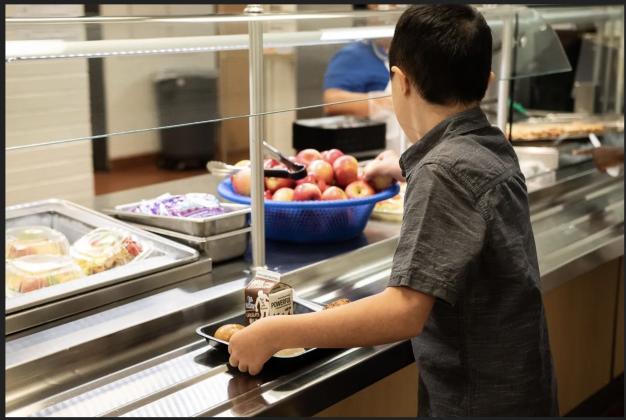 A fifth-grader at Roosevelt Middle School in south Oklahoma City grabbed an apple for lunch on Aug. 11, 2022, the first day of school. (Whitney Bryen/Oklahoma Watch)