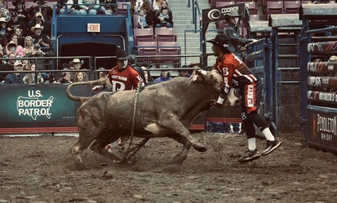 Madill native Dekevis Jordan goes head to head with a bull during the Chickasaw Nation World Championship Rodeo Bullfighting finals while Austin Ashley watches. The finals were held September 15 and 16 at the Hardy Murphy Coliseum in Ardmore. (Courtesy photo)