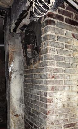 The old boiler chimney in the courthouse basement. Visible at the top is the location where the boiler smoke stack entered the chimney, and at the bottom is the coal ash cleanout. Photo courtesy of Gary Henry