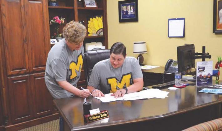 Banc First’s Sheri Owens (left) and Will Bain (right) review loan documents on April 21. Owens, the Madill branch’s vice president and loan processor, and Bain, the Madill branch’s vice president and commercial lender, have are among a group of bankers who have worked extra hours to process additional loans under the Payroll Protection Program Matt Caban • The Madill Record