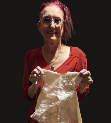 Angela Hudson displays an infant burial gown she and her fellow Movers and Shakers members donate to grieving parents. Courtesy photo
