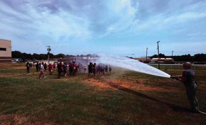 Above and below right: The Madill Fire Department kicked off the beginning of the school year by soaking the band during the Back to School Bash. Below left: MFD Chief Mike Idleman bought some children ice cream from the ice cream truck. Courtesy photos