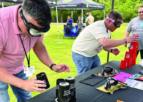Two men try out the Drunk Busters goggles at a booth set up at Wheelock Academy. One of the tests given while wearing the Drunk Busters goggles is stacking cups into a pyramid. The goggles simulate how being impaired can affect your depth perception and reaction time. Courtesy photo