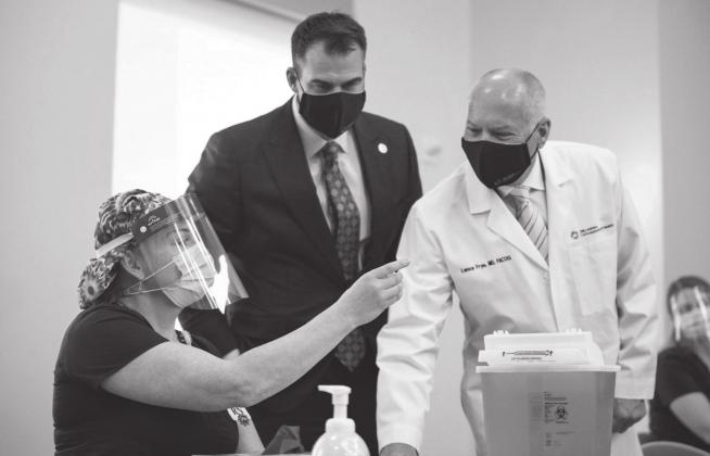 In this file photo, Oklahoma State Commissioner of Health Dr. Lance Frye, right, is shown with Gov. Kevin Stitt, middle, and ICU nurse Erica Arrocha, left, last December before she administered the state's first COVID-19 vaccine at Integris Baptist Medical Center in Oklahoma City. (Whitney Bryen/Oklahoma Watch)