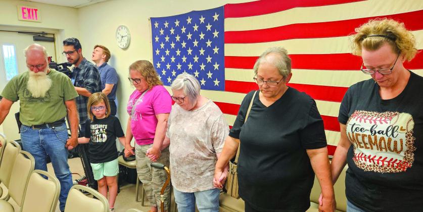Supporters of Kasey Cox, who was terminated as Kingston police chief, join hands in prayer after the meeting. Matt Swearengin