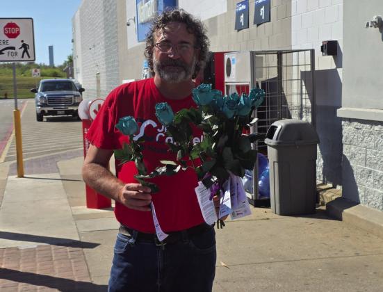 Josh Cantrell handed out flowers in front of Walmart to raise awareness about domestic violence. Charles White • The Madill Record