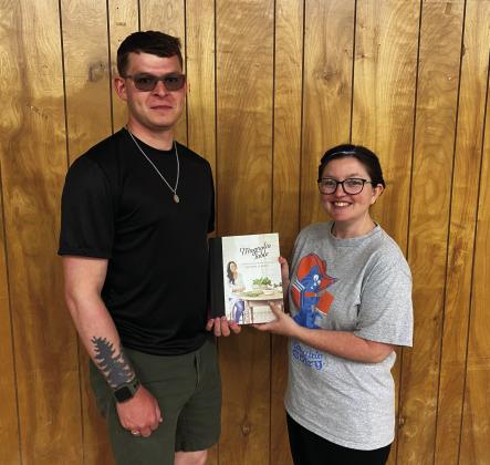Connie Barden, right, presents Dakota Hanks his cookbook titled Magnolia Table. Hanks won the book in a drawing held during the library's annual book sale. Courtesy photo