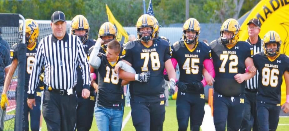 The Madill Wildcats walk down with Mason Campbell, the honorary Wildcat, to participate in the coin toss. Summer Bryant • The Madill Record