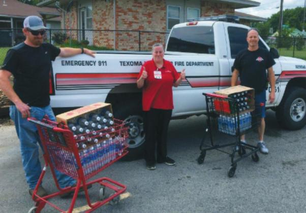 Tracy Cissel, Kimberly Afilkins, and Todd Cissel pose next to the donations of water given to Texoma Volunteer Fire Department from the Kingston family Dollar Courtesy photo
