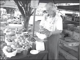 Phyllis Lammon weighs green beans during a farmers market event before offering her fruits and vegetables to the community.