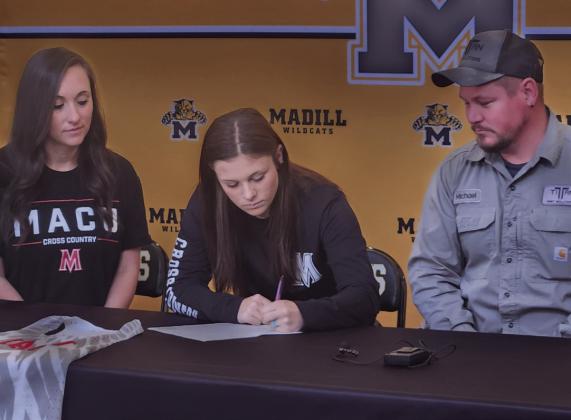 Kaia Henry signs her college letter of intent to attend Mid American Christian University while her family watches. Andrea Dunlap • The Madill Record