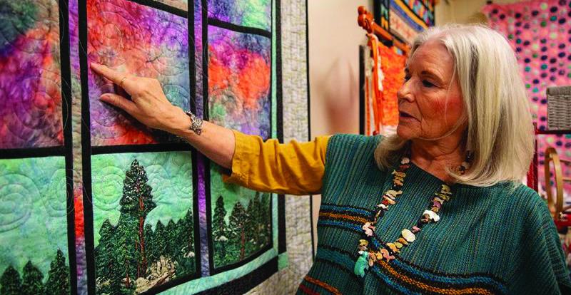 Mary Wilds examines “Storm Clouds over the Arbuckle,” one of many quilts and textiles the Chickasaw artists plans to show at the Southeastern Art Show and Market (SEASAM) scheduled Oct 4-5 in Tishomingo, Oklahoma. Courtesy photo