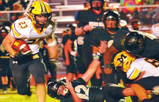 Sophmore Holden McGahey, #23, runs with the ball while Tyner Rushing, #8, takes the brunt of the tackles during the Madill v. Marietta game. Summer Bryant •The Madill Record
