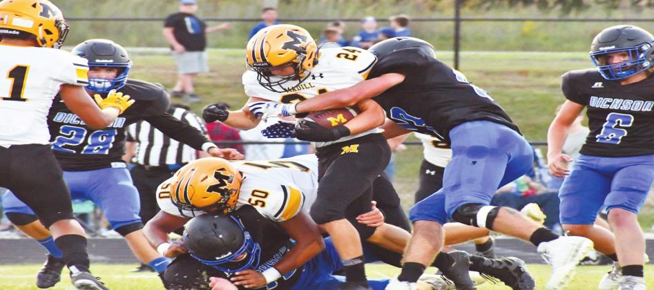 Madill junior running back Brandon Stephens, #24, runs through a line of Dickson Comets while senior Armando Sanchez, #50, clears the path. Jennifer Rushing