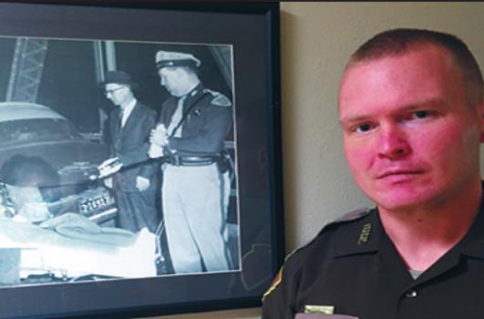 Garrett Schulze stands by a photo of his grandfather as a trooper. Courtesy photo