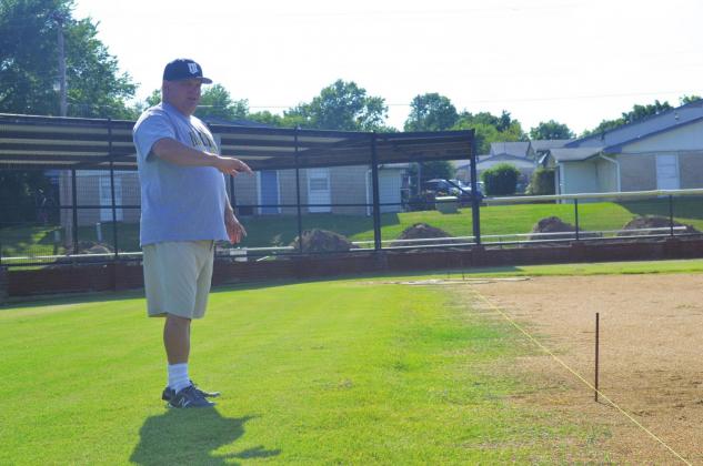 New Madill High School fast-ptich softball coach Brett Vann shows where the first base line will be redrawn at Tom Reynolds Field. The home of the Lady Wildcats will also have its awning expanded later this summer. Matt Caban • The Madill Record